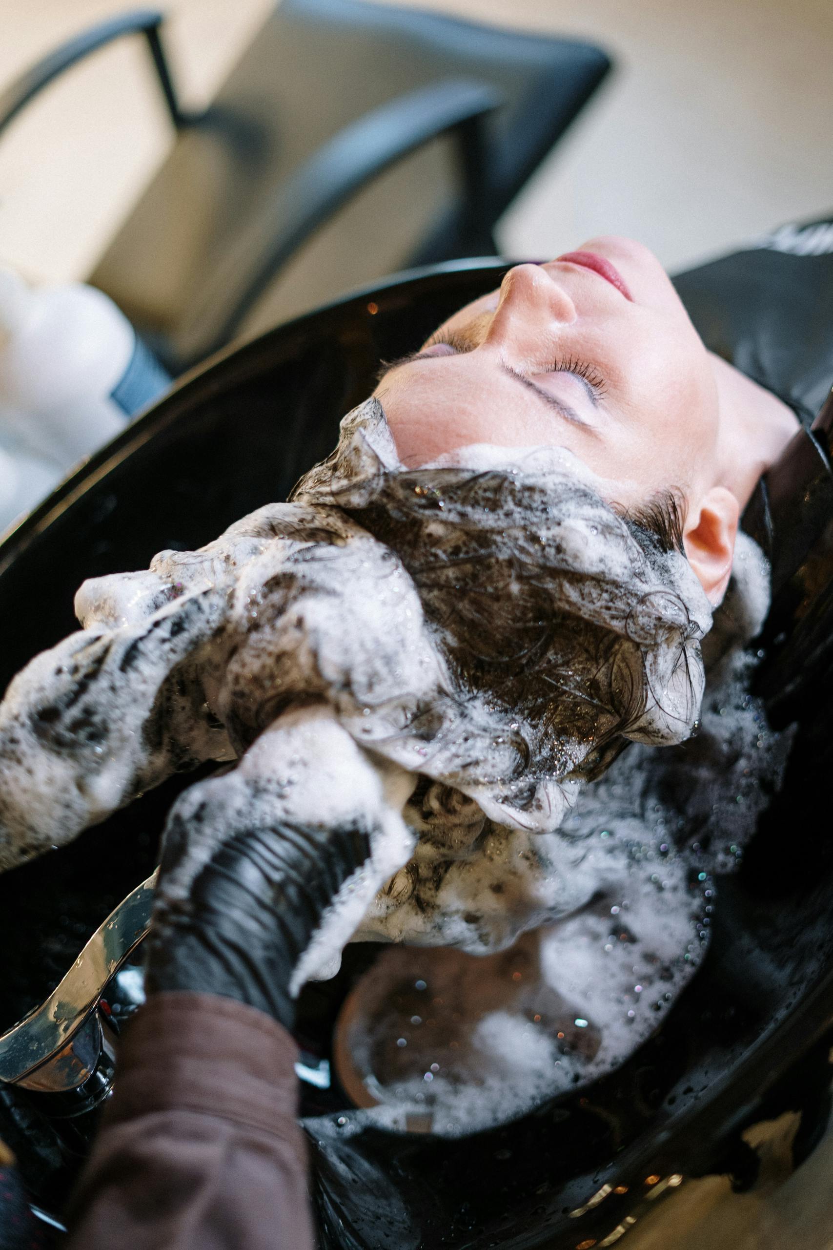 A woman receiving hairstyling services in a salon, showcasing professional grooming.