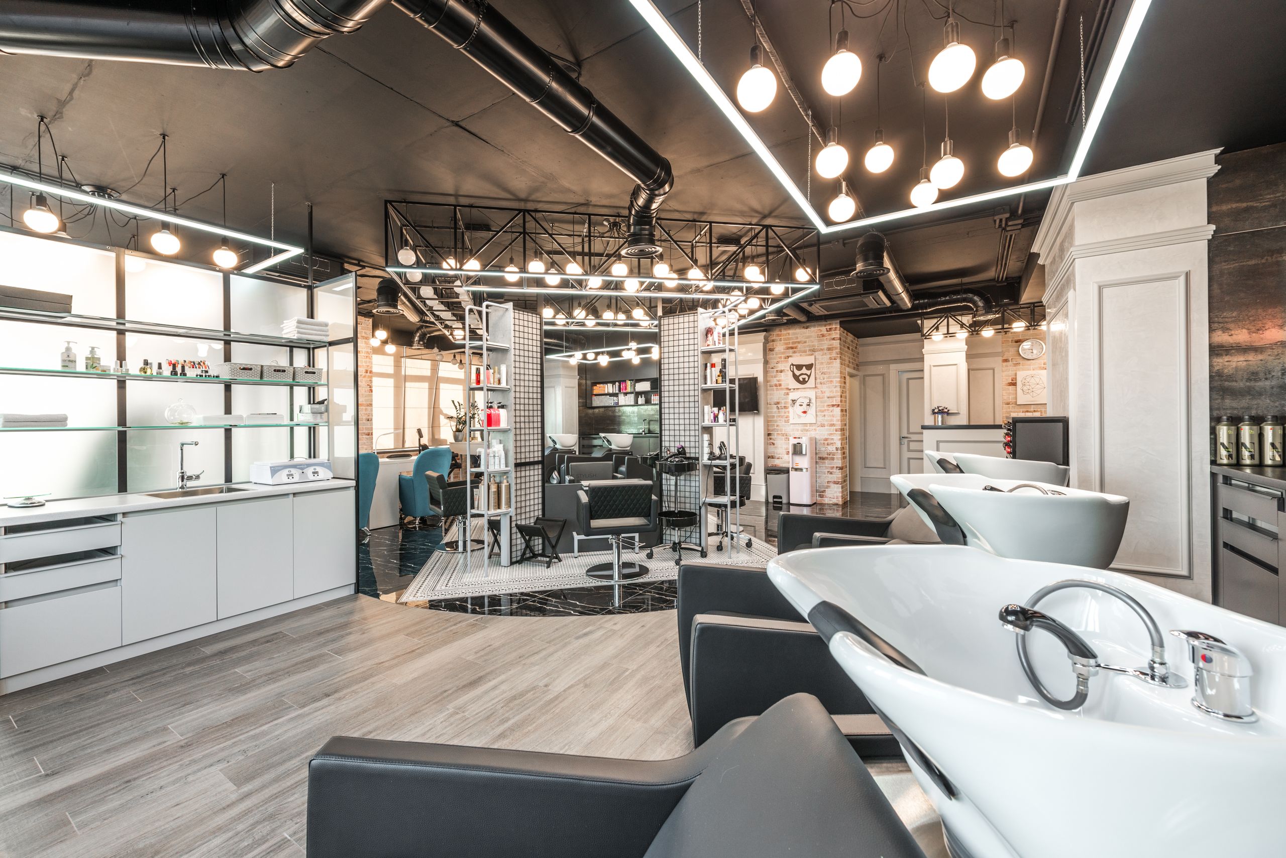 Backwash chairs with sinks placed in spacious modern beauty salon with stylish design and various cosmetology products with professional equipment